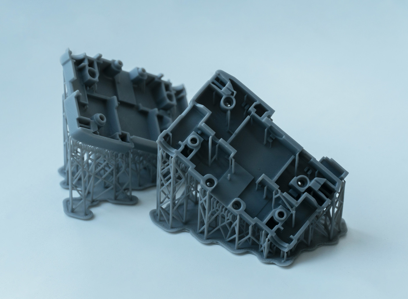 Two washed stereolithography (SLA) printed parts in grey against a bright background. Courtesy of EnCata PD under the Unsplash License